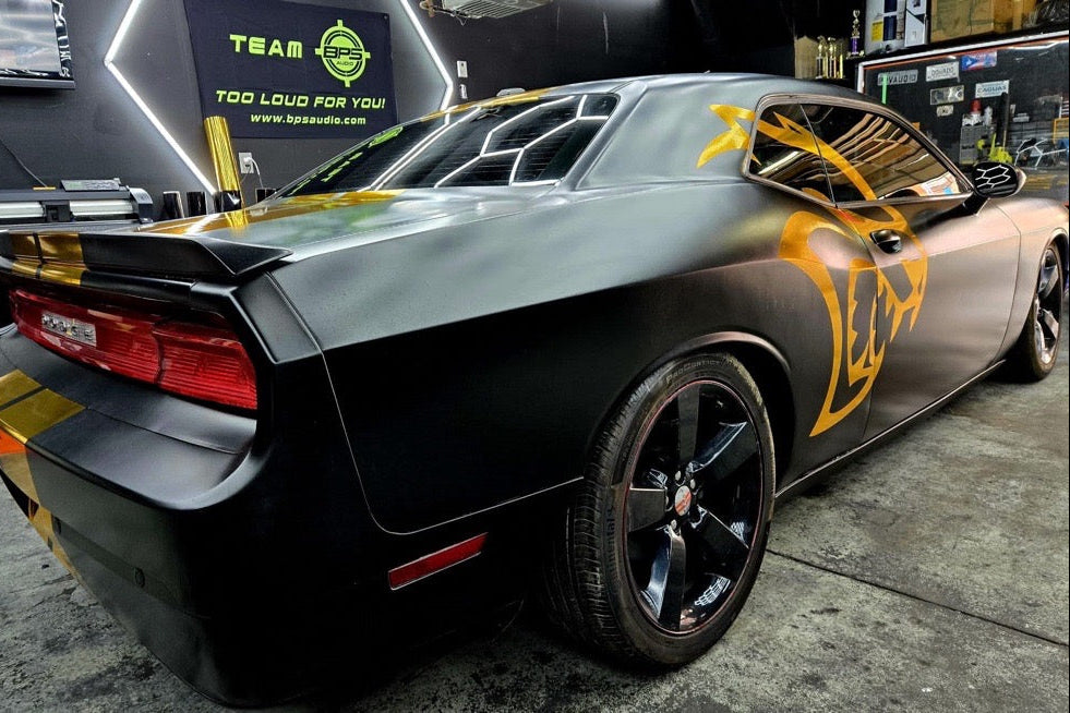 Black and gold muscle car with visible branding in a garage setting